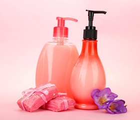 Liquid and hand-made soaps on pink background