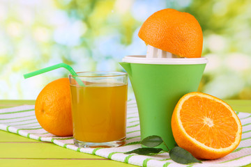 Citrus press, glass of juice and ripe oranges