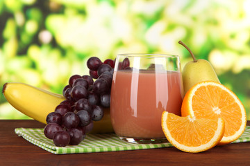 Glass of fresh juice on table on bright background