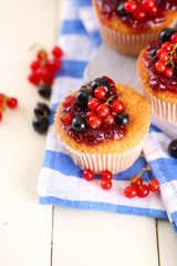 Tasty muffins with berries on white wooden table