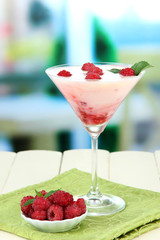 Raspberry milk dessert in cocktail glass, on bright background