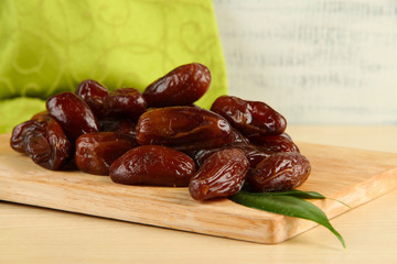 Dried dates on wooden stand on table on fabric background