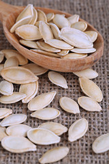 Pumpkin seeds in spoon on sackcloth background
