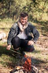 mature smile man sitting at campfire