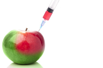 Apple in two colors with a syringe. Concept for GMO.