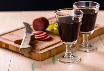 Red wine with salami and grapes on old wood table and some grape