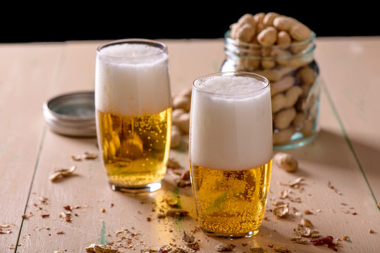 Beer with peanuts on old wood table