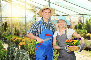 Male and female gardeners with basket and shovel in hothouse