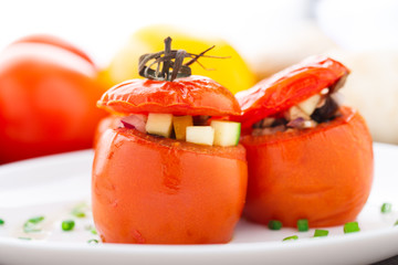 Three stuffed tomatoes on a white plate