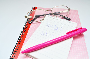 Pink pen notebook and glasses word ready