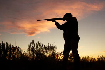 Poster Hunter in silhouet schieten bij zonsondergang © natureguy