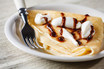 Close up of French style crepe with cream and chocolate sauce