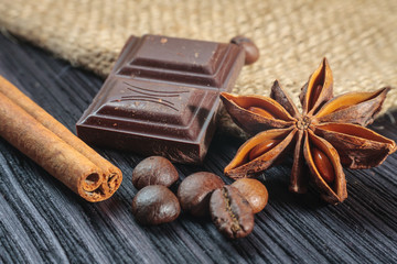 Chocolate bar and spices on wooden table