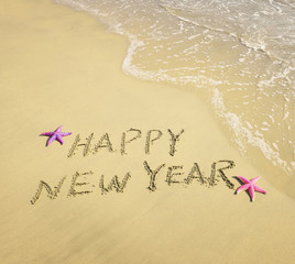 Fototapeta premium happy new year written in the sand