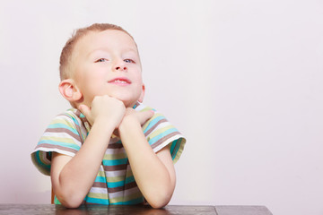 Portrait of pensive thoughtful blond boy child kid at the table