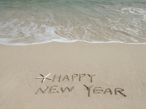 happy new year written in the sand