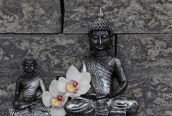 Zwei Buddhafiguren mit Orchidee