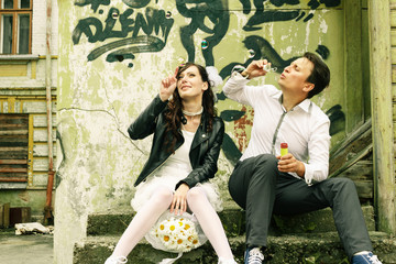 unusual loving wedding couple near wall with graffiti thrown hou