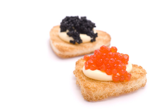 Two Heart-Shaped Toasts with Red and Black Caviar on White Sauce