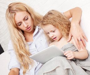 Mother and daughter wiht tablet at sofa