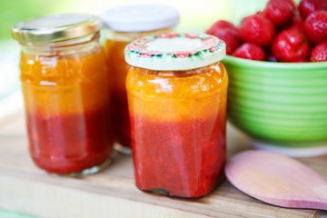 Homemade strawberry jam in different jars and fresh ripe strawbe