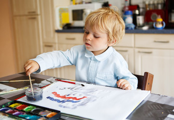 Adorable boy of two years drawing with paints.