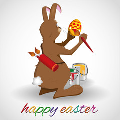 Osterhase malt Osterei mit Farbe an