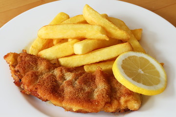 Paniertes Schweineschnitzel mit Pommes frites und Zitrone