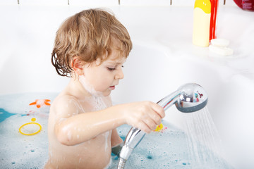 Cute little toddler boy of two years having fun by taking bath i