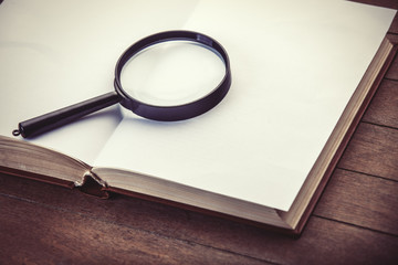Loupa and book on wooden table