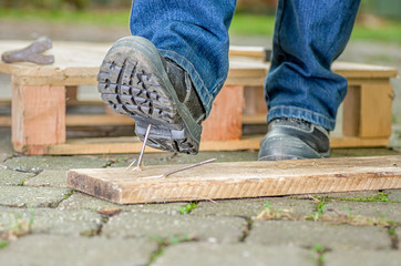 Arbeiter mit Sicherheitsschuhen tritt in einen Nagel