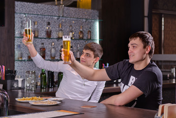 Two young men raising their beers in a toast