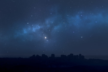 Fototapeta na wymiar City landscape at night with star filled sky, nebula and galaxy