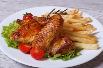 Two fried chicken wings with a crispy crust and fries