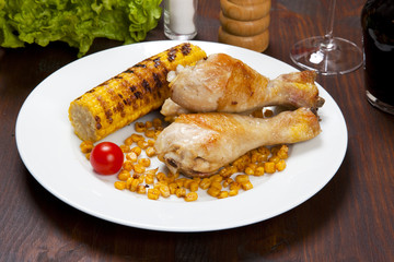 chicken thigh with a boundary of corn cob and salad