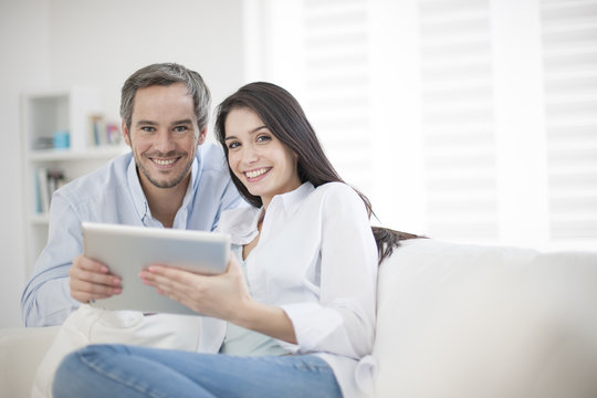 Cheerful couple using digital tablet at hom