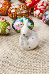 Obraz premium Easter eggs and ceramic rabbit on jute background