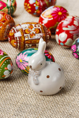 Easter eggs and ceramic rabbit on jute background