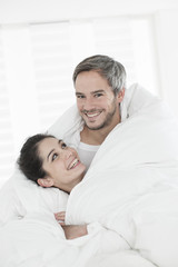 cheerful young couple wrapped in their quilt