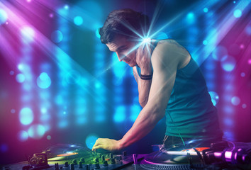 Fototapeta na wymiar Dj mixing music in a club with blue and purple lights