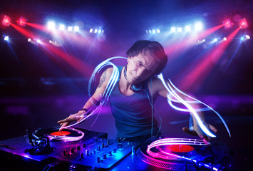 Disc jockey playing music with light beam effects on stage