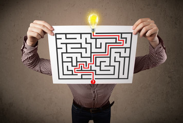 Businessman holding a paper with a labyrinth on it in front of h
