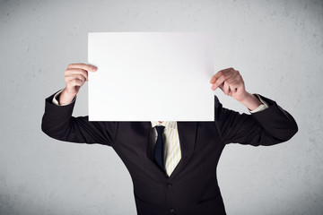 Businessman holding in front of his head a paper with copy space