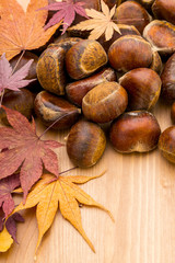 Chestnut and dry maple leave on wooden background