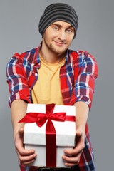 Stylish young man in shirt and beanie hat with gift box