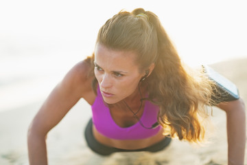 Fitness young woman doing push ups on beach