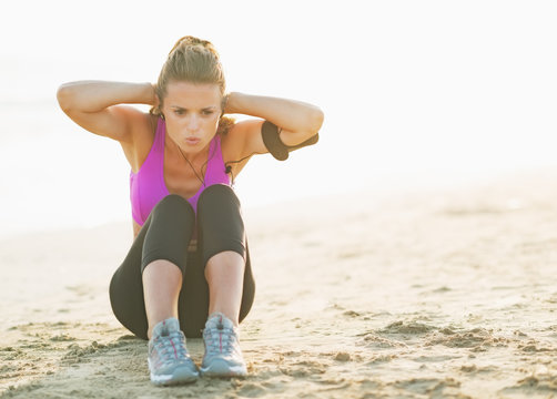 Healthy Young Woman Doing Abdominal Crunch On Beach