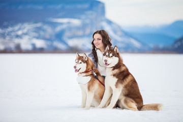 young girl playing with siberian husky dogs in winter park © A.Kazak
