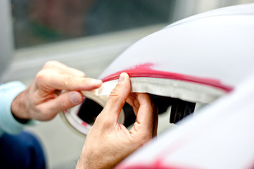 Mechanic preparing a car for painting by protecting the edges