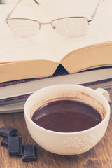 Cup of chocolate on a wooden table with books